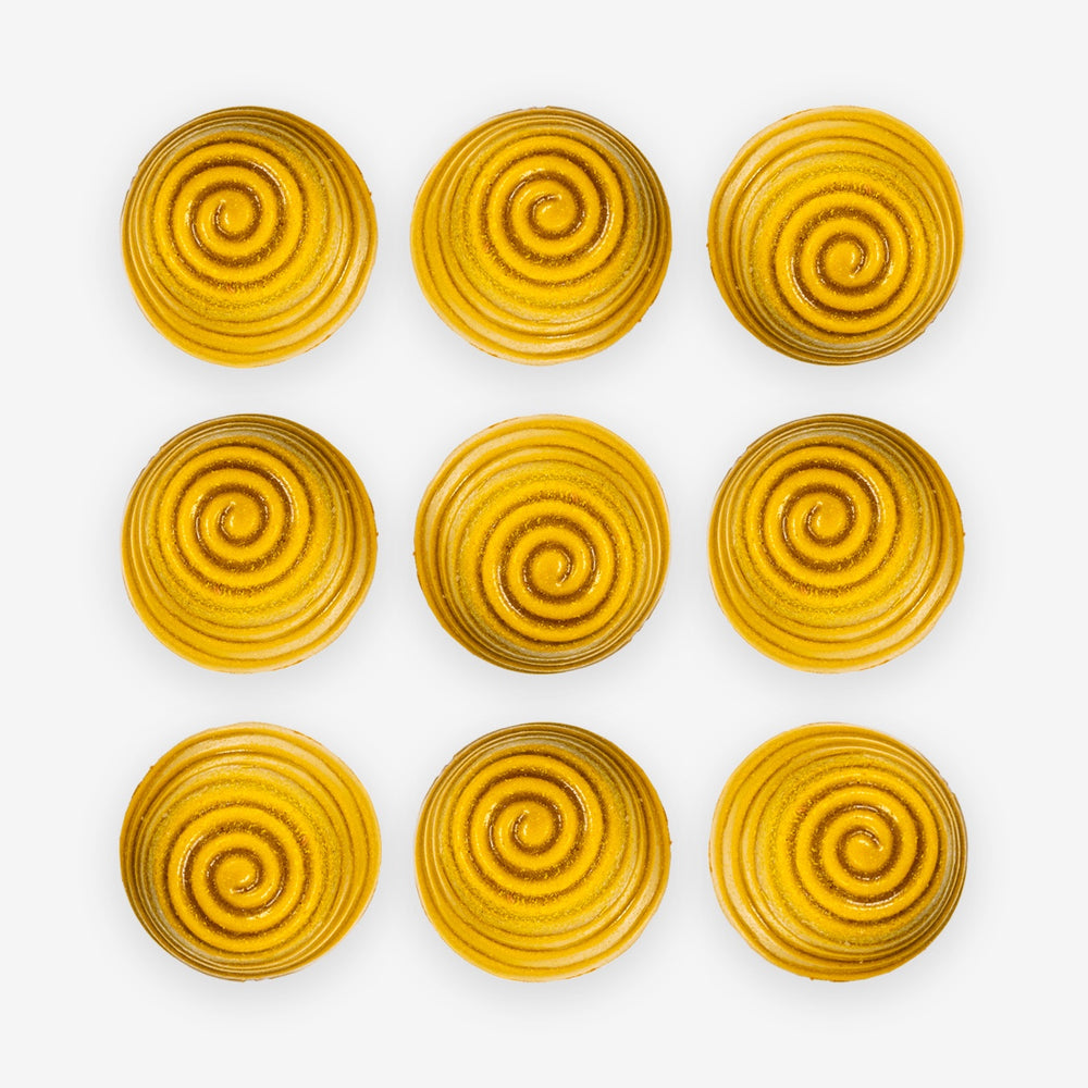 Nine yellow spiral-patterned Manuka honey chocolates arranged in a 3x3 grid on a white background.