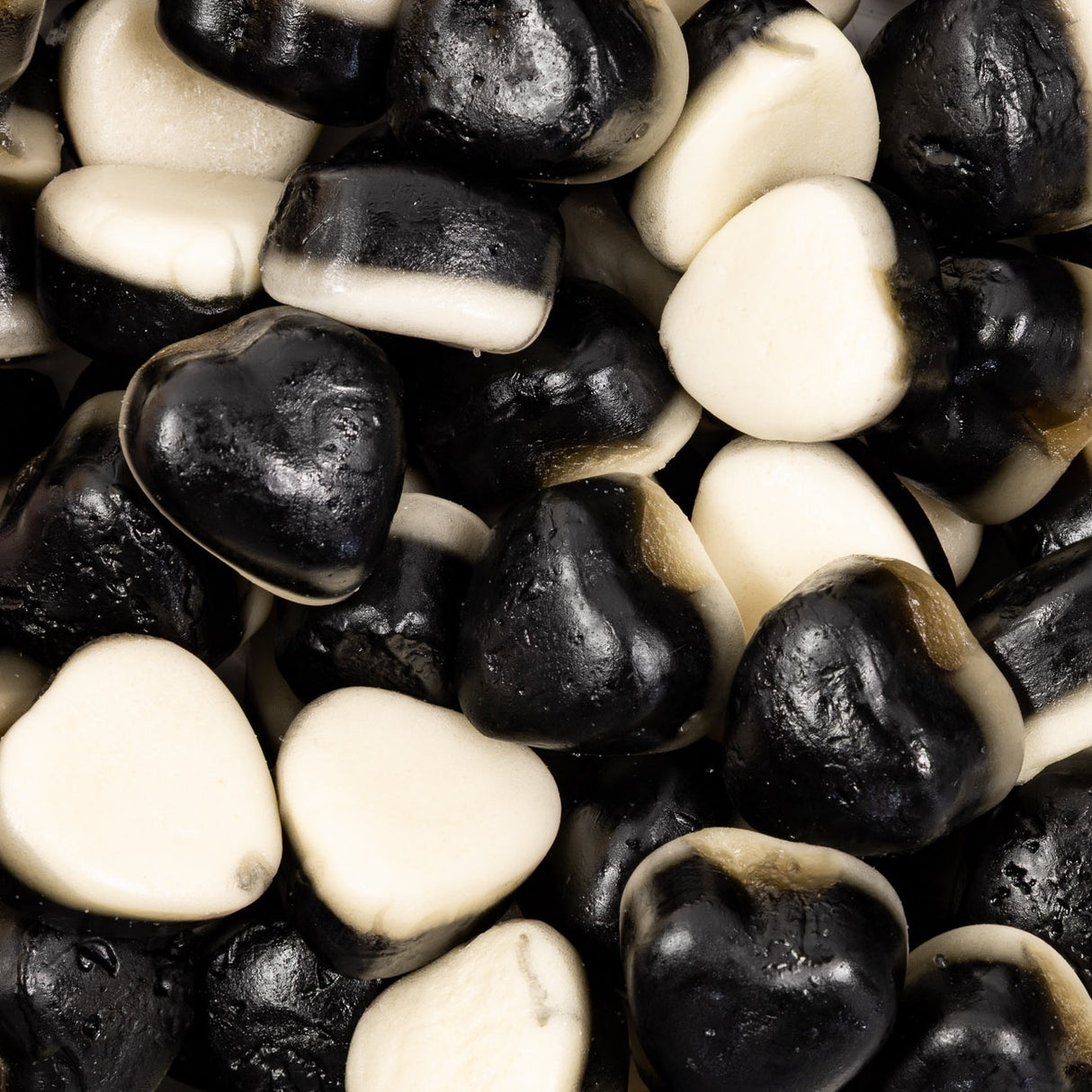 Close-up of black and white heart-shaped licorice gummies.
